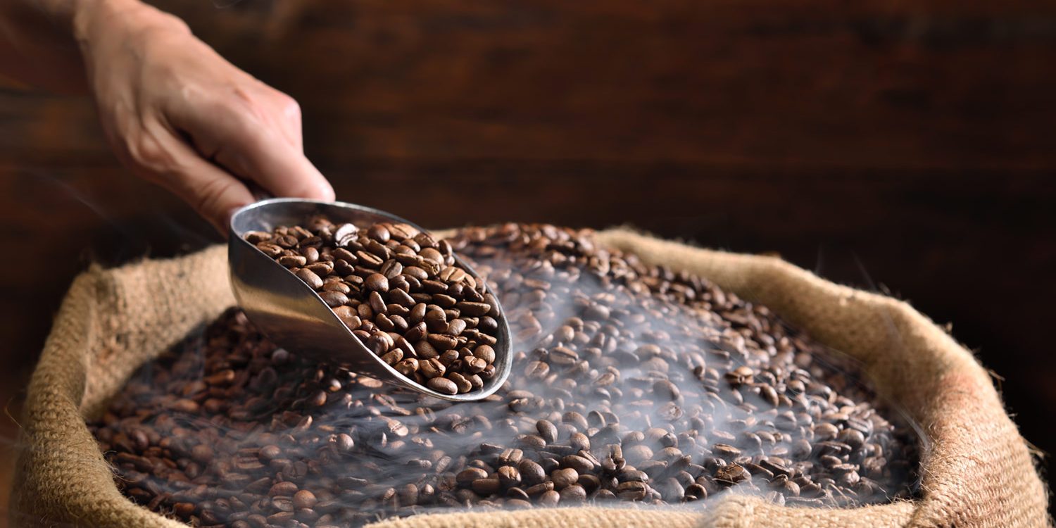 High-quality freshly roasted coffee beans, exuding rich aroma and deep brown color, ready to be ground and brewed for a delightful sensory experience.